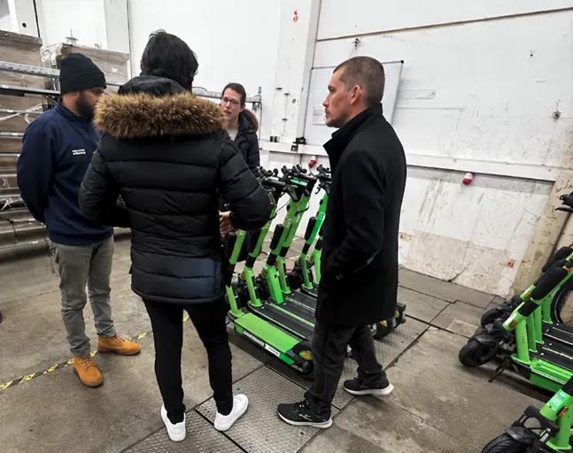 فنّي من Fleetser يتفقّد أسطول سكوترات كهربائية مع البائع في مستودعه